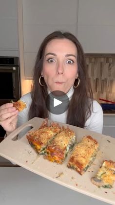 a woman is holding up a tray with food on it and looking at the camera