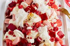 a white platter filled with fruit and whipped cream toppings on top of raspberries