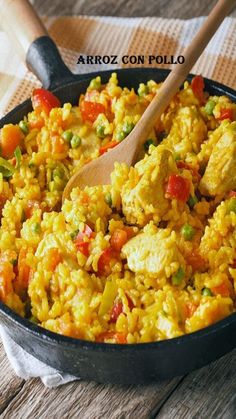 a pan filled with rice and vegetables on top of a wooden table