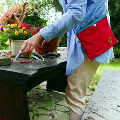 a woman is using gardening shears to trim flowers on a table outside in the sun