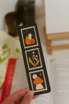 a person holding up a bookmark with stamps on it