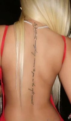 the back of a woman's neck with tattoos on it and words written in cursive writing