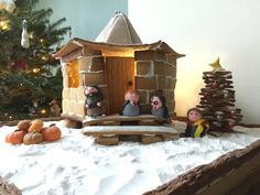 a christmas scene with three figurines in front of a gingerbread house and tree