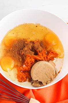 a bowl filled with different types of food on top of a orange cloth next to a whisk