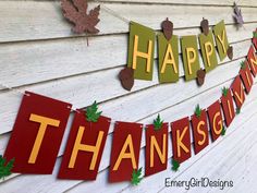 a happy thanksgiving banner hanging on the side of a building with leaves and acorns