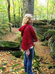 a woman standing in front of a tree with leaves on the ground and rocks around her