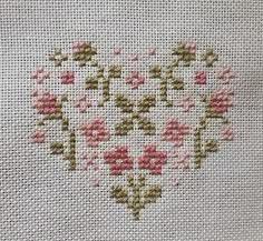 a cross stitch heart with pink flowers on it