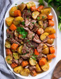 a white platter filled with meat and veggies