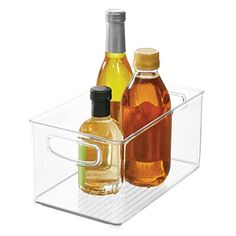 two bottles of oil and one bottle of vinegar in a clear container on a white background