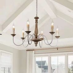 a chandelier hanging from the ceiling in a living room with windows and curtains