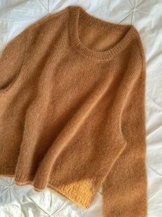 a brown sweater laying on top of a bed