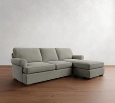 a large sectional couch sitting on top of a wooden floor next to a white wall