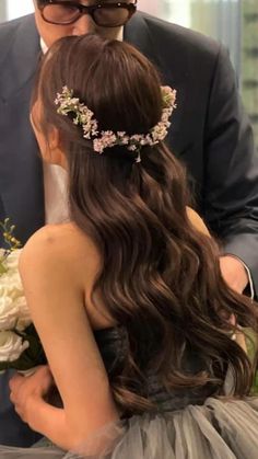 a man in a suit standing next to a woman wearing a flowered headpiece