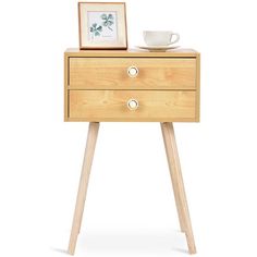 a small wooden table with two drawers and a cup on the top, next to a framed photograph