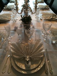 the table is set with silver and white dishes, place settings, and napkins