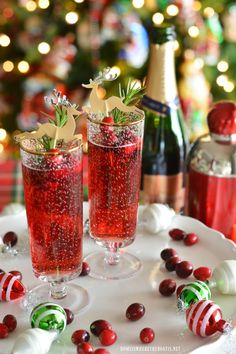 two glasses filled with liquid sitting on top of a white plate next to christmas decorations