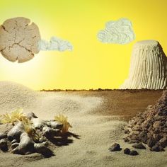 a desert scene with rocks and plants in the foreground, two clouds above them