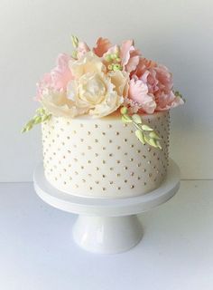 a white cake with pink and yellow flowers sitting on top of it's stand