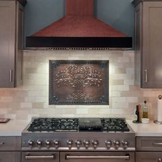 a stove top oven sitting inside of a kitchen under a red metal hood over it's burners