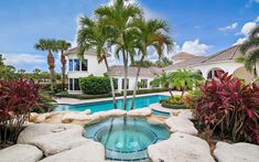 a pool surrounded by palm trees next to a house