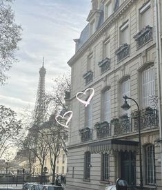 the eiffel tower is in the distance with cars parked on the side of the street