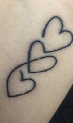 a tattoo with two hearts on the wrist