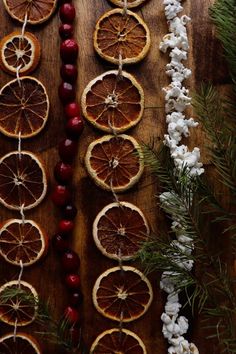 dried orange slices and cherries are arranged on a wooden table with pine cones, cotton candy, and christmas decorations