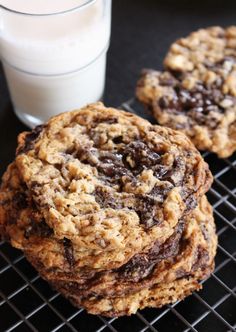 three cookies cooling on a rack next to a glass of milk