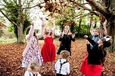 a group of young children standing next to each other on top of leaf covered ground