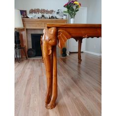 an elephant head carved into the top of a wooden table in front of a fireplace