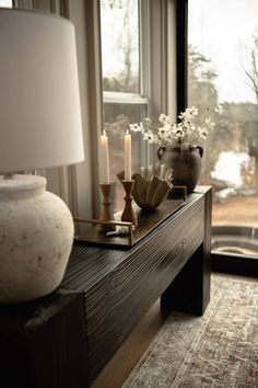 a table with candles, vases and flowers on it in front of a window