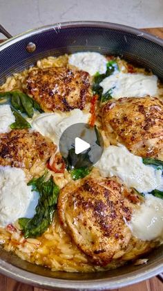 a pan filled with chicken and spinach covered in white sauce on top of a wooden table