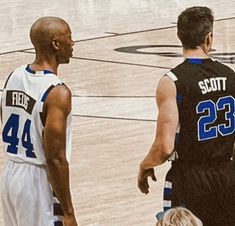 two basketball players talking to each other on the court