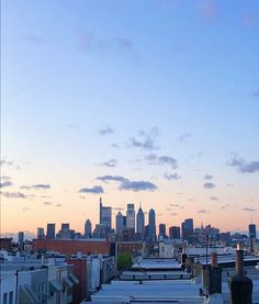 the city skyline is seen in the distance from rooftops at dusk, with no clouds