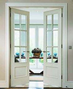 an open door leading to a dining room with two vases on the table in front of it