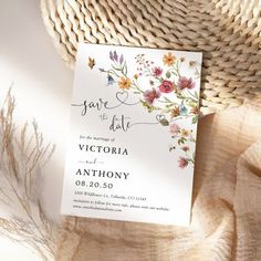 an elegant floral save the date card is displayed on top of a woven table cloth