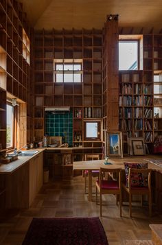 a room filled with lots of wooden bookshelves next to a table and chairs