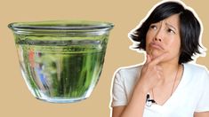 a woman is looking at a green liquid in a glass cup with her hand on her chin