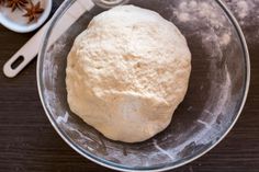 a ball of dough sitting in a glass bowl on top of a table next to spices