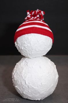 a white snowman with a red and white striped hat on it's head