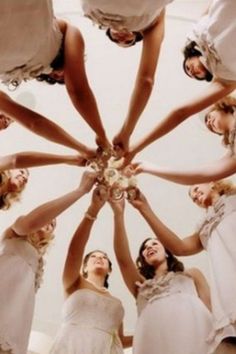 a group of bridesmaids standing in a circle holding their hands together to form a star