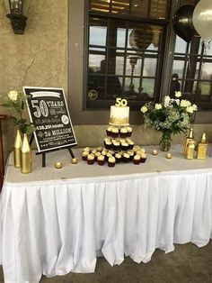 a table topped with lots of cupcakes covered in frosting next to a sign