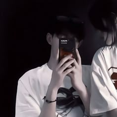 a woman is holding her cell phone up to her face while wearing a white shirt