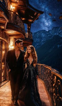 a man and woman standing on a balcony at night with the stars in the sky