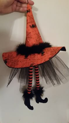 a hand holding an orange witch's hat on top of a table