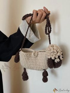 a woman holding a crocheted sheep purse