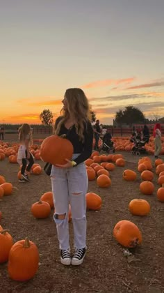 a woman standing in a field full of pumpkins