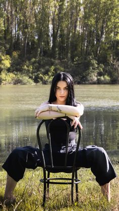 a woman sitting in a chair next to a body of water