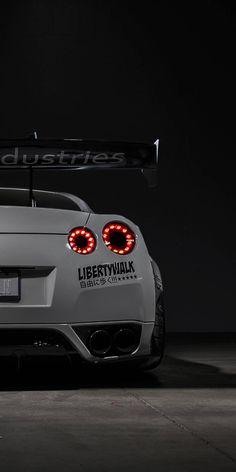 the back end of a white sports car with lights on it's taillights