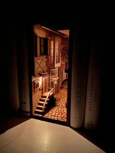 an open door to a room with books on the floor and stairs leading up to it